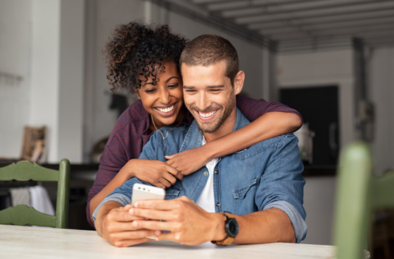A couple hugging and looking at an iphone
